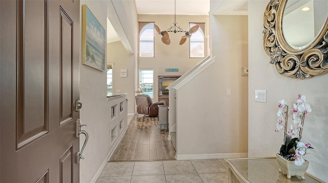 entrance foyer featuring an inviting chandelier, baseboards, stairway, and light tile patterned flooring