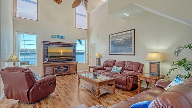 living area featuring a towering ceiling, baseboards, and wood finished floors