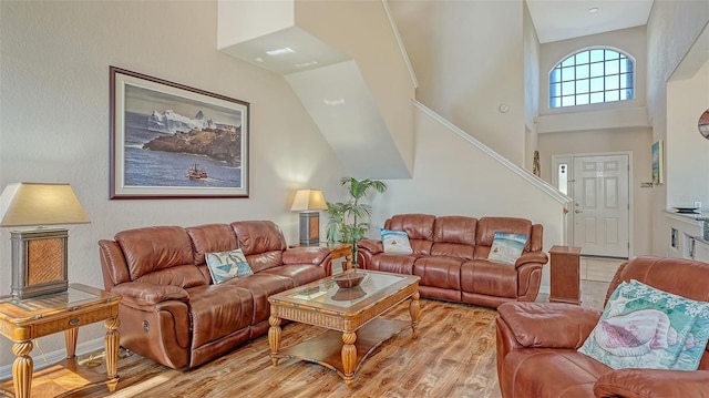 living room featuring a towering ceiling and light hardwood / wood-style floors