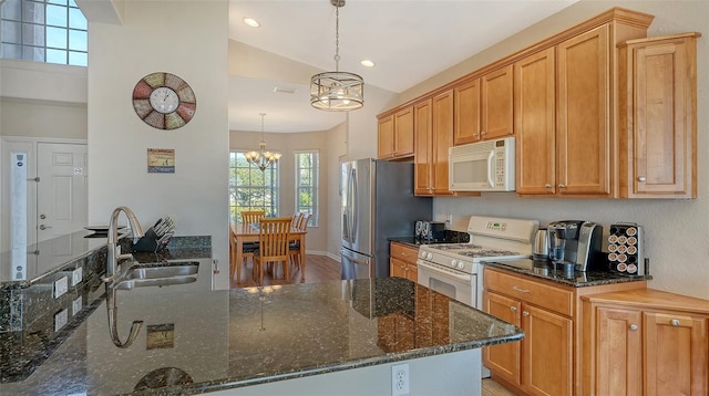 kitchen with hanging light fixtures, white appliances, and dark stone counters