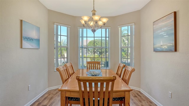 dining room featuring light wood-style flooring, baseboards, and a chandelier