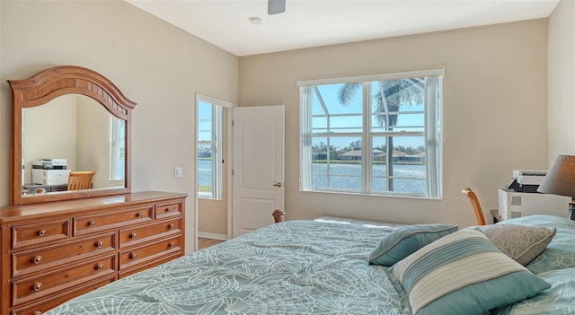 bedroom featuring ceiling fan and a water view