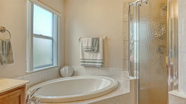 bathroom with a stall shower, a garden tub, and vanity