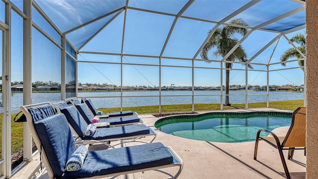 pool featuring glass enclosure, a patio, and a water view