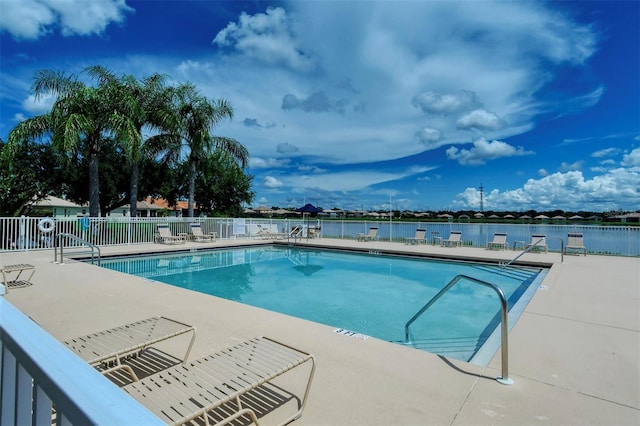 community pool featuring a water view, fence, and a patio