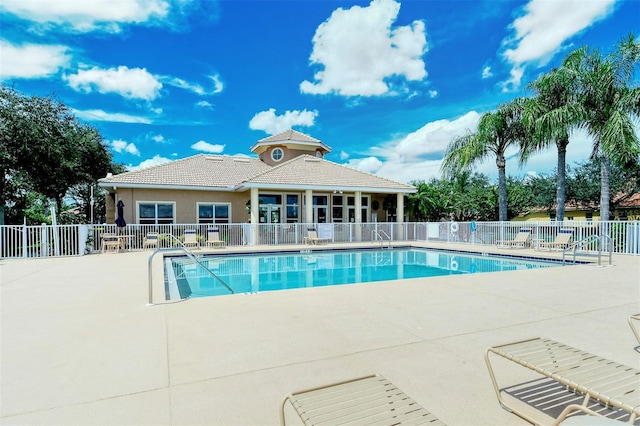 community pool with a patio and fence