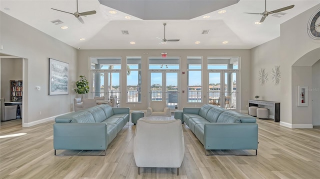 living room with ceiling fan, high vaulted ceiling, and light wood-type flooring