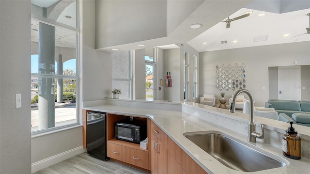 kitchen with a ceiling fan, light wood-style flooring, open floor plan, black microwave, and a sink