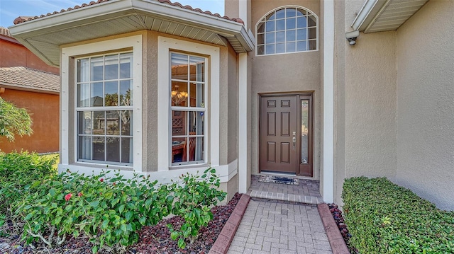 doorway to property featuring a tiled roof and stucco siding