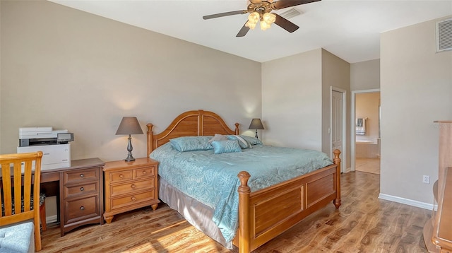 bedroom featuring light wood finished floors, ceiling fan, baseboards, and ensuite bathroom