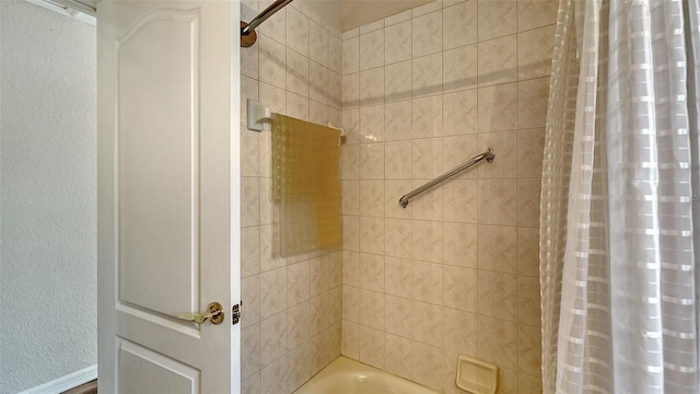 bathroom featuring a textured wall and shower / bath combination with curtain