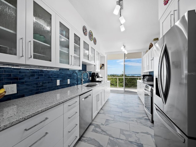 kitchen featuring stainless steel appliances, white cabinetry, sink, and decorative backsplash