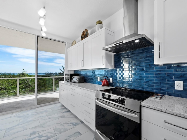 kitchen with white cabinetry, stainless steel range with electric stovetop, wall chimney range hood, light stone countertops, and backsplash