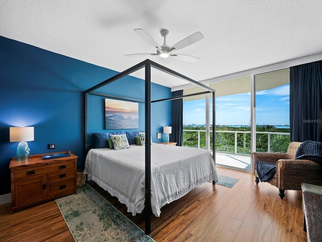 bedroom featuring expansive windows, wood-type flooring, access to exterior, and a textured ceiling