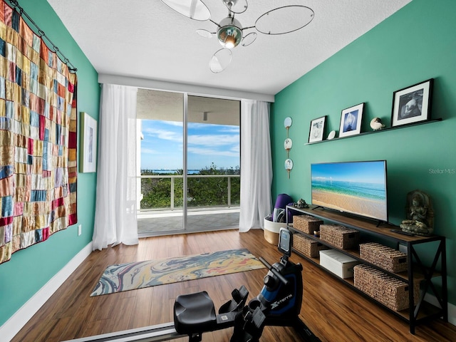 workout room with hardwood / wood-style flooring, a wall of windows, and a textured ceiling