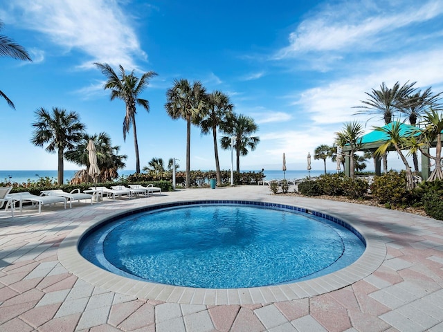 view of pool featuring a water view and a patio area