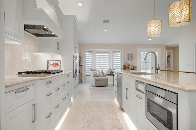 kitchen with white cabinetry, light stone countertops, sink, and hanging light fixtures