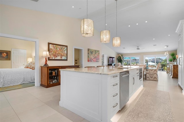 kitchen featuring a kitchen island with sink, light stone counters, pendant lighting, and white cabinetry