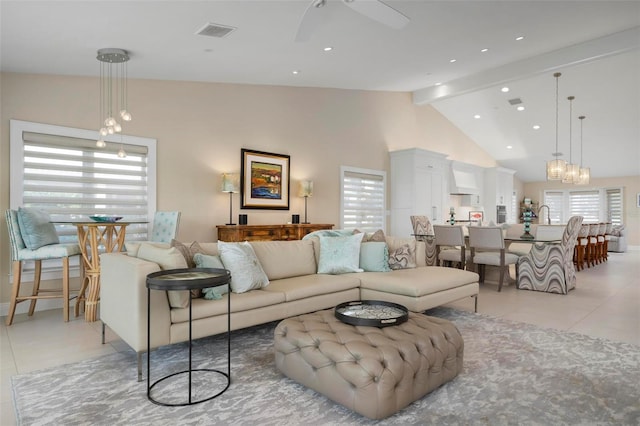 tiled living room featuring beamed ceiling, ceiling fan with notable chandelier, and high vaulted ceiling