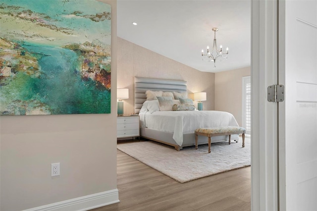 bedroom with wood-type flooring, vaulted ceiling, and an inviting chandelier