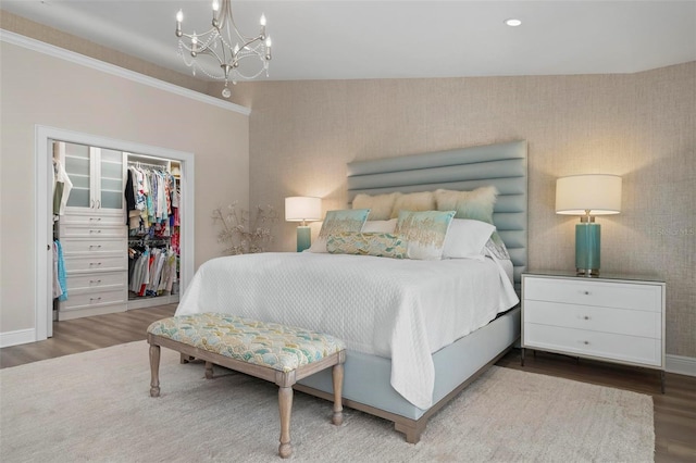 bedroom featuring an inviting chandelier, hardwood / wood-style floors, a walk in closet, and a closet