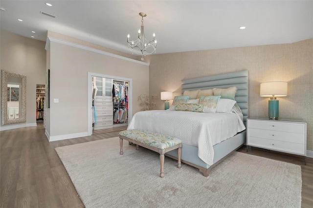 bedroom with a walk in closet, hardwood / wood-style floors, an inviting chandelier, and a closet