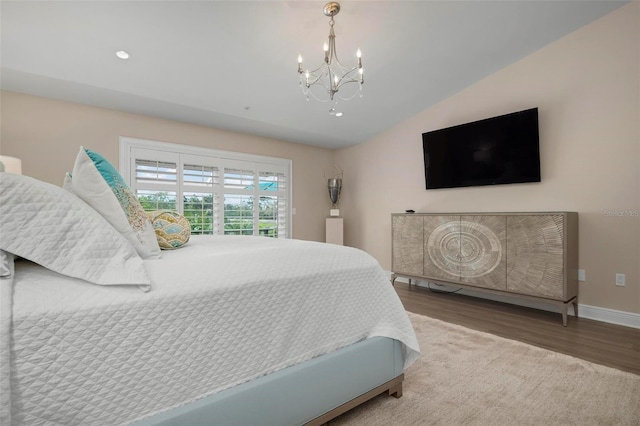 bedroom with an inviting chandelier, wood-type flooring, and vaulted ceiling