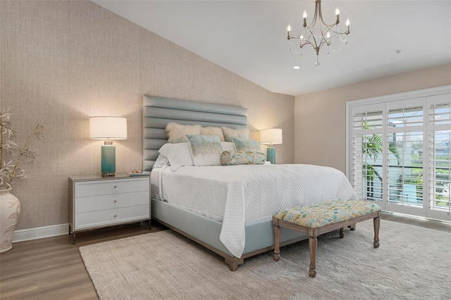 bedroom with hardwood / wood-style flooring, a chandelier, and vaulted ceiling