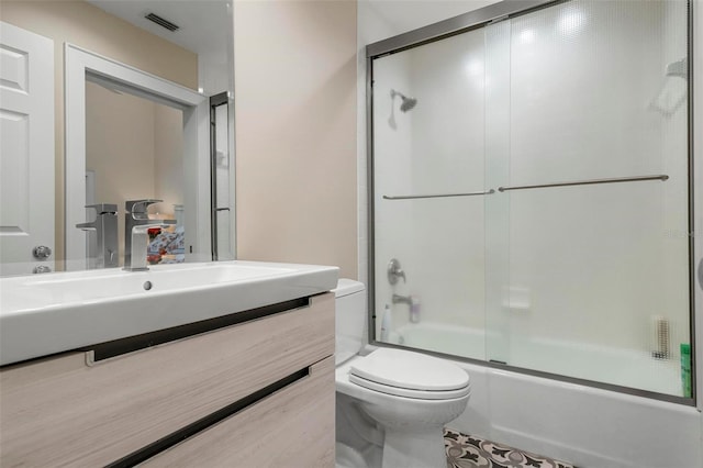 full bathroom with enclosed tub / shower combo, vanity, and toilet