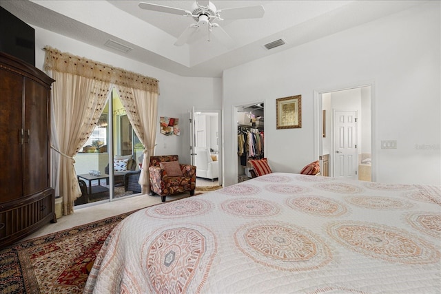 carpeted bedroom featuring ceiling fan, a raised ceiling, access to outside, a walk in closet, and a closet