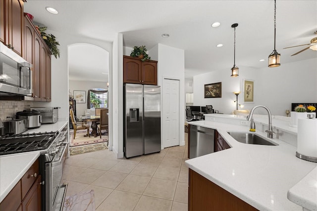 kitchen with pendant lighting, sink, light tile patterned floors, stainless steel appliances, and decorative backsplash