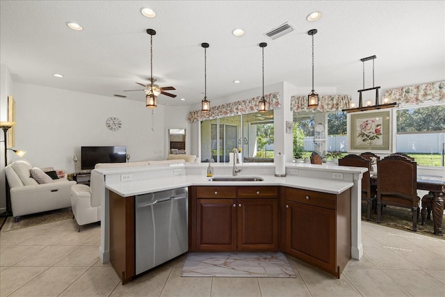 kitchen with stainless steel dishwasher, hanging light fixtures, sink, and a center island with sink