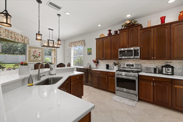 kitchen featuring hanging light fixtures, backsplash, stainless steel appliances, and sink