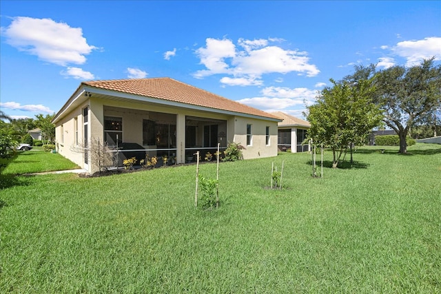 rear view of property featuring a sunroom and a lawn