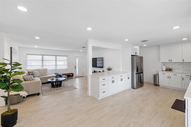 kitchen featuring white cabinetry, stainless steel fridge, light hardwood / wood-style floors, and backsplash