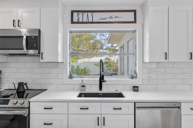 kitchen featuring stainless steel appliances, sink, white cabinets, and backsplash