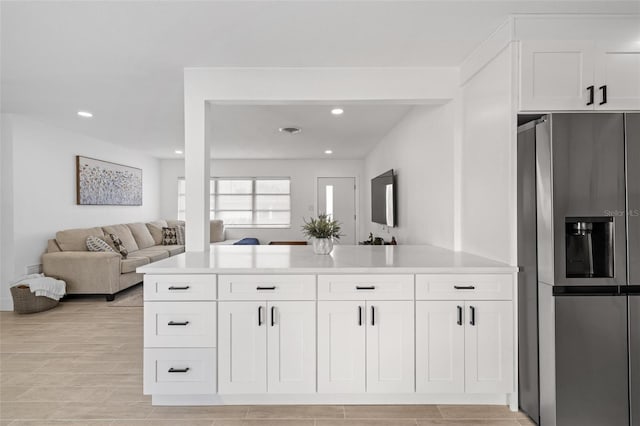 kitchen featuring white cabinetry, stainless steel fridge with ice dispenser, and kitchen peninsula