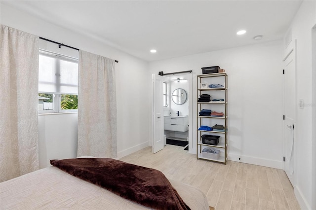 bedroom featuring a barn door and light hardwood / wood-style flooring