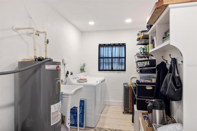 clothes washing area with light hardwood / wood-style flooring, water heater, and washing machine and clothes dryer