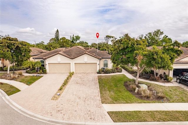 mediterranean / spanish-style house featuring a garage, a tiled roof, decorative driveway, a front yard, and stucco siding