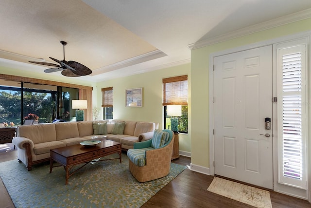 living room featuring baseboards, ceiling fan, dark wood-type flooring, and crown molding