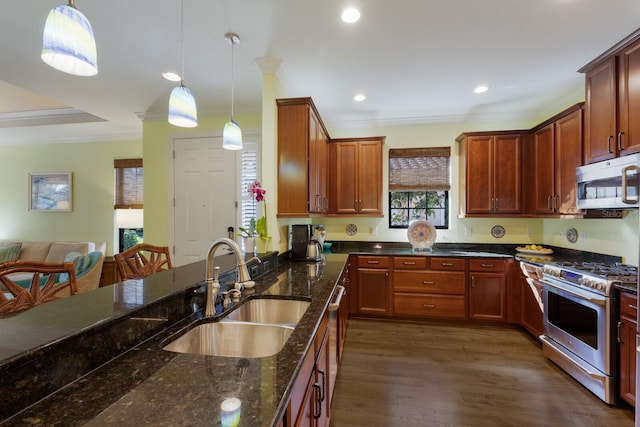 kitchen with dark stone counters, appliances with stainless steel finishes, a sink, and decorative light fixtures