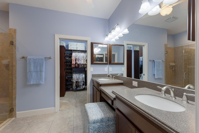 full bath with a sink, a walk in closet, visible vents, and a shower stall