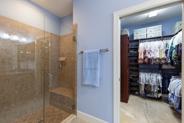 full bath featuring a stall shower, a spacious closet, and baseboards