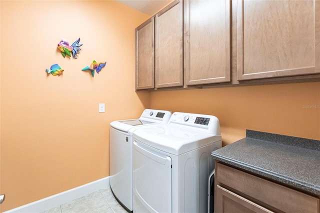 washroom featuring washer and dryer, cabinet space, baseboards, and light tile patterned flooring