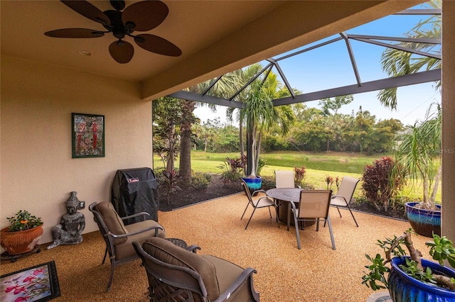 view of patio / terrace featuring glass enclosure, grilling area, a ceiling fan, and outdoor dining space