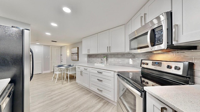 kitchen featuring white cabinetry, decorative backsplash, light hardwood / wood-style flooring, and stainless steel appliances