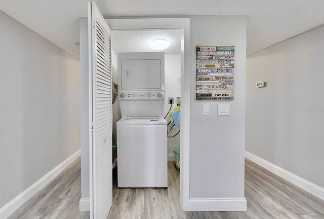 laundry area featuring light hardwood / wood-style flooring, a textured ceiling, and stacked washer / dryer