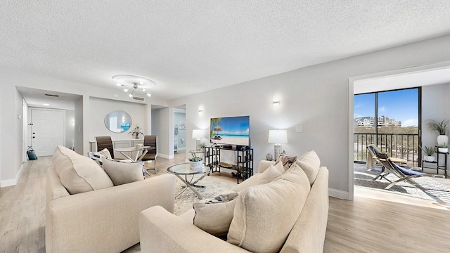 living room with a textured ceiling and light wood-type flooring