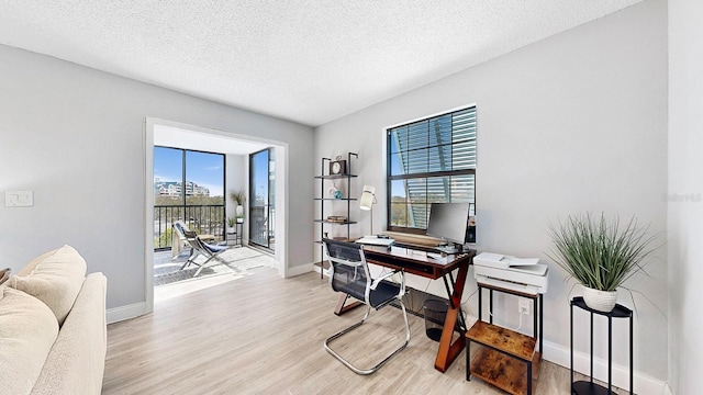 home office with a textured ceiling and light hardwood / wood-style flooring